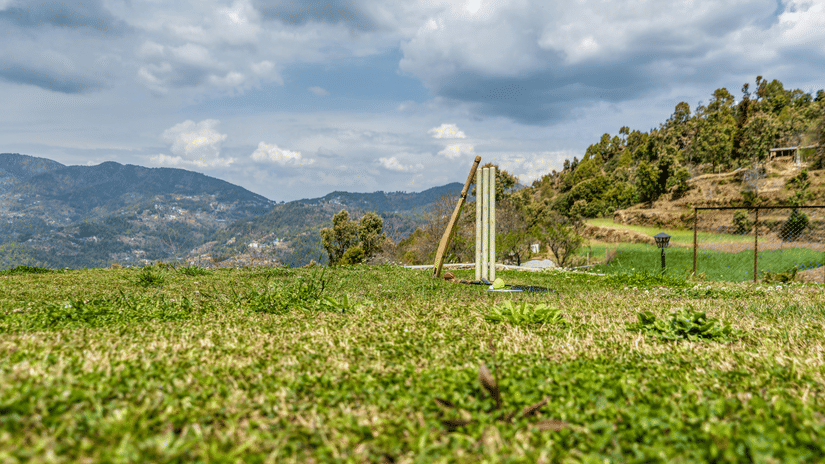  Picture showing a cricket bat, a Set of Stumps, and a red ball along with  a Badminton Racquet and a Shuttle.