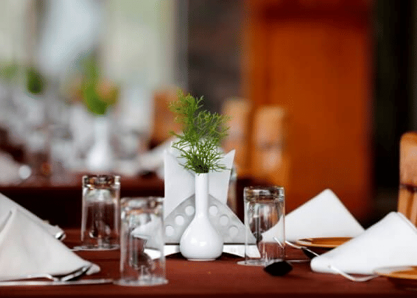 A finely set dining table with white napkins, glasses, and a small vase, ready for a meal